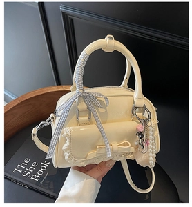 Détail du sac bowling en cuir verni crème avec dentelle, nœuds et breloques perles
