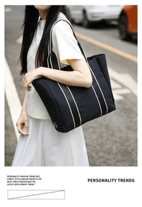 Detailed close-up of large black canvas tote bag with white stripes and sun logo