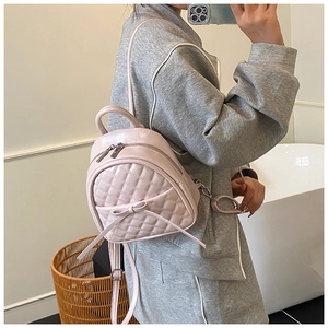 Détail du sac à dos en cuir matelassé rose avec nœud décoratif et fermeture éclair argent