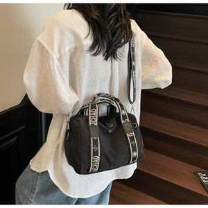 Dettaglio della borsa Boston in nylon nero con tracolla UCHAO in un contesto lifestyle