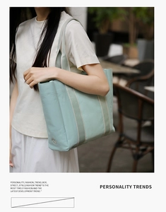 Close-up of mint green canvas tote bag featuring striped webbing and sun embroidery