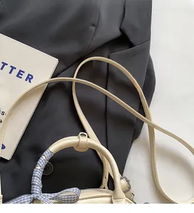Détail du sac à main en simili cuir crème avec foulard en soie et bandoulière fine