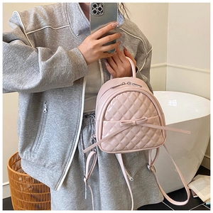 Détail du mini sac à dos rose matelassé avec nœud élégant et texture à losanges brillants