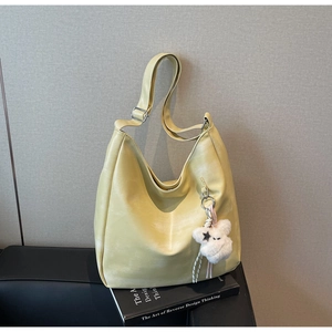 Détail d'un sac hobo crème avec bandoulière réglable et pendentif en peluche doux