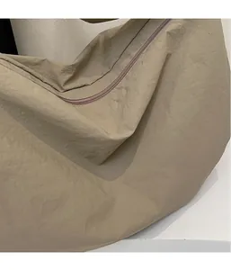 Détail macro de la texture du nylon kaki et fermeture éclair lisse sur un sac besace