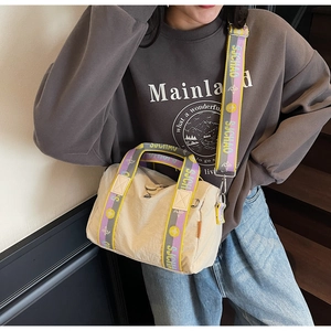 Dettaglio della borsa beige in nylon con coulisse e tracolla a fiori e fibbie in metallo