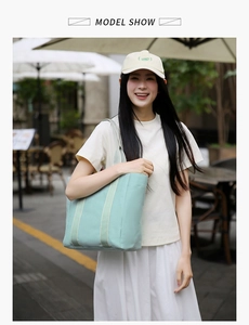Outdoor shot of a mint green canvas tote bag with white webbing straps on street background