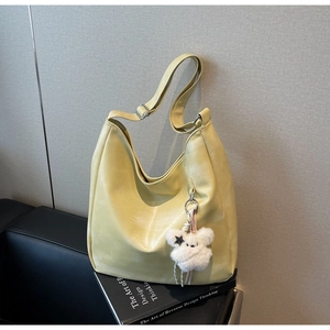 Détail du sac hobo en cuir PU jaune clair avec un petit pendentif en peluche blanche
