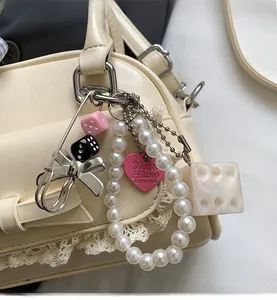 Gros plan d'un bijou de sac en perles avec dés et cœur rose sur un sac à main chic