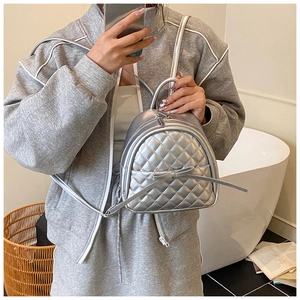 Mini sac à dos argenté matelassé avec détail de nœud dans un décor intérieur élégant