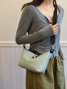 Minimalist light green dumpling crossbody bag with a wide black shoulder strap for women