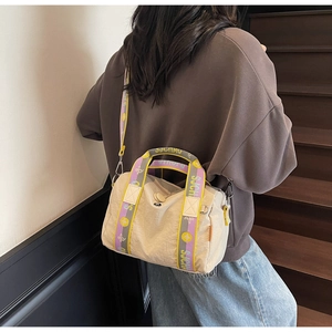 Dettaglio della borsa a cilindro beige con spalline colorate e chiusura a zip