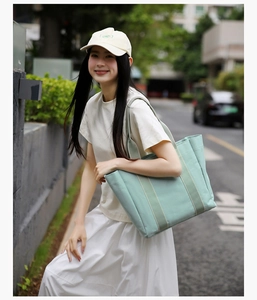 Close-up of mint green canvas tote bag with striped shoulder strap for casual wear