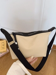 Beige dumpling style crossbody bag with nylon fabric and wide black woven shoulder strap