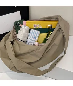 Vue intérieure montrant la grande capacité du sac bandoulière en nylon kaki avec objets