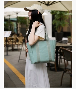 Detailed view of mint green canvas tote bag with reinforced handles on a model