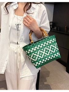 Sac seau tissé vert et blanc avec poignées en bambou présenté dans un décor de style