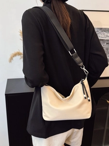Chic beige crossbody dumpling bag with wide black strap shown on a model for daily style