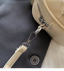 Détails macro de la fermeture éclair et du crochet argentés sur un sac crème