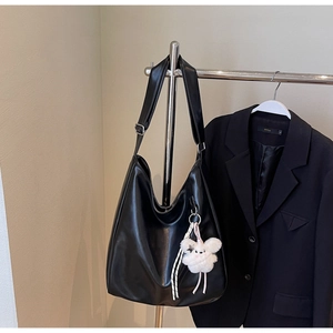 Détail d'un sac à bandoulière en cuir PU brillant noir avec charm agneau en peluche blanc