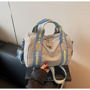 Dettaglio borsa a spalla in nylon grigio con tracolla jacquard blu e gialla a contrasto