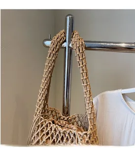 Detail of hollow crochet woven tote with a beige drawstring inner bag on a metal stand