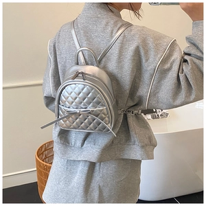 Détail du mini sac à dos matelassé argenté avec nœud porté sur le dos du modèle