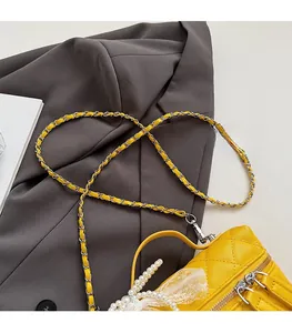 Détail du mini sac boîte jaune matelassé avec breloque perle et nœud en dentelle