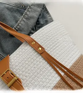 Dettaglio della borsa tote in paglia con tracolla in pelle marrone e fibbia dorata