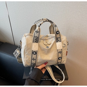 Dettaglio della borsa boston in nylon beige con tessuto strutturato e manici logati
