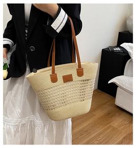 Dettaglio della borsa tote in paglia intrecciata con manici in pelle marrone