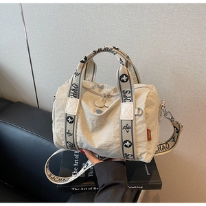 Dettaglio della borsa a tracolla in nylon bianco panna con ampia tracolla in tessuto