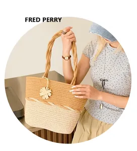 Detail of a two-tone woven straw tote bag featuring rope handles and a star charm