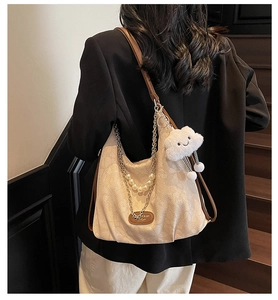 Chic beige canvas tote bag with pearl chain detail and cloud plush charm worn on shoulder