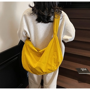 Détail du sac bandoulière en nylon jaune en forme de croissant porté par un mannequin