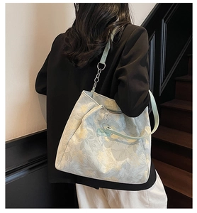 Close-up of a floral jacquard tote bag with leather straps worn by a model in a stairwell