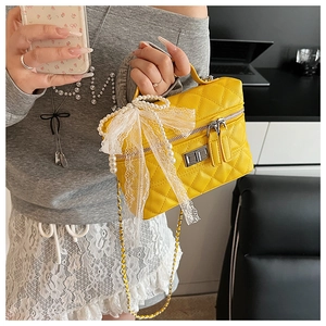 Détail du sac boîte jaune matelassé avec poignée perle et décoration dentelle