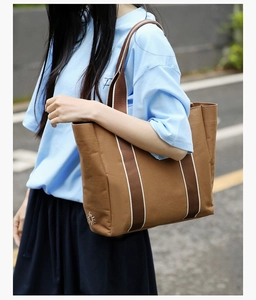 Detailed sun embroidery on a large brown canvas tote bag with striped shoulder straps