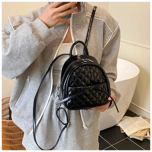 Gros plan d'un sac à dos noir matelassé avec finition brillante et détail de nœud élégant