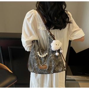 Detail of floral tote bag with pearl handle and plush cloud charm worn on shoulder
