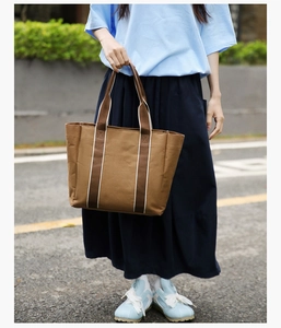 Close-up of brown canvas tote bag with contrast striped handles for casual commute