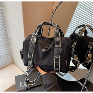 Dettaglio borsa in nylon nero con tracolla jacquard, motivo JCHAO e fiori di giglio