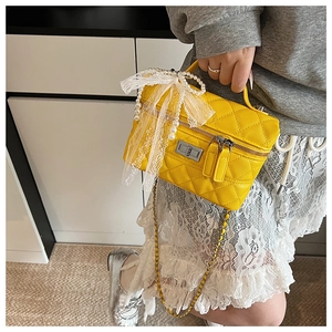 Sac boîte matelassé jaune avec perles et nœud en dentelle tenu par un mannequin