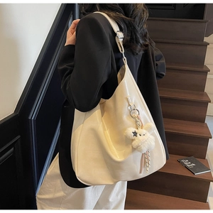Détail du sac hobo en cuir souple beige avec charm lapin en peluche sur un escalier en bois