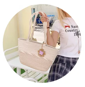 Detailed close-up of a woven tote bag featuring a dual-tone design and floral pendant