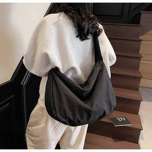 Vue détaillée d'un grand sac bandoulière croissant en nylon noir porté par un modèle