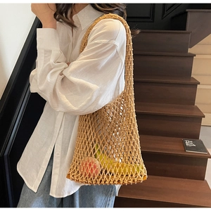 Detail of woven bucket bag featuring hollow mesh net and brown leather base with fruit