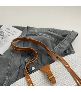 Dettaglio della borsa tote intrecciata bianca con manici in pelle marrone e rivetti