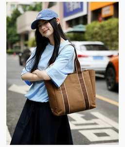 Close-up of brown canvas tote bag with vertical striped webbing and spacious design