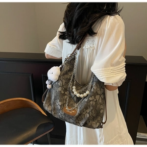 Detail of floral crossbody bag with silver chain, pearls, and a cute plush bear pendant